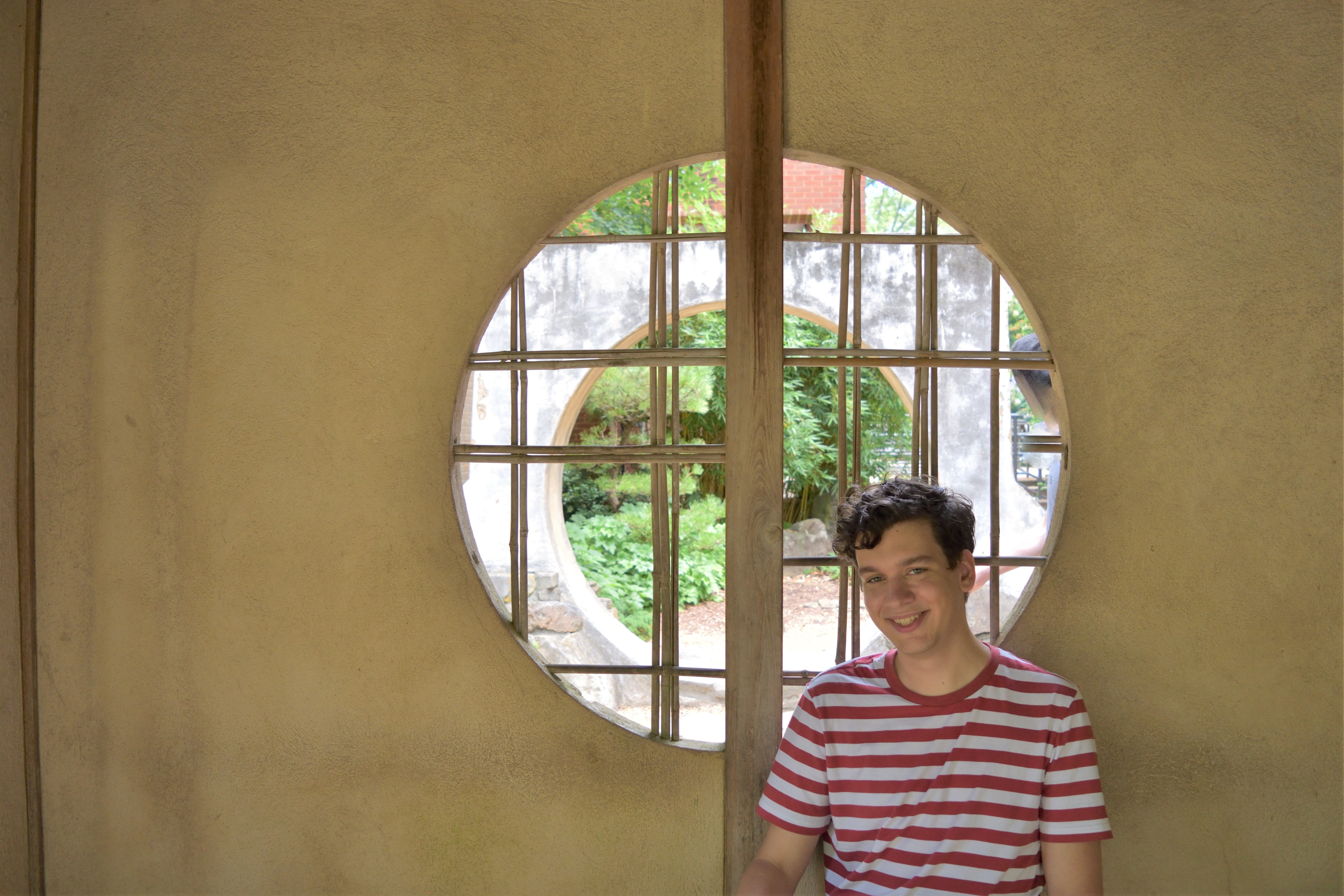 A man wearing a striped shirt, sitting in front of a circle